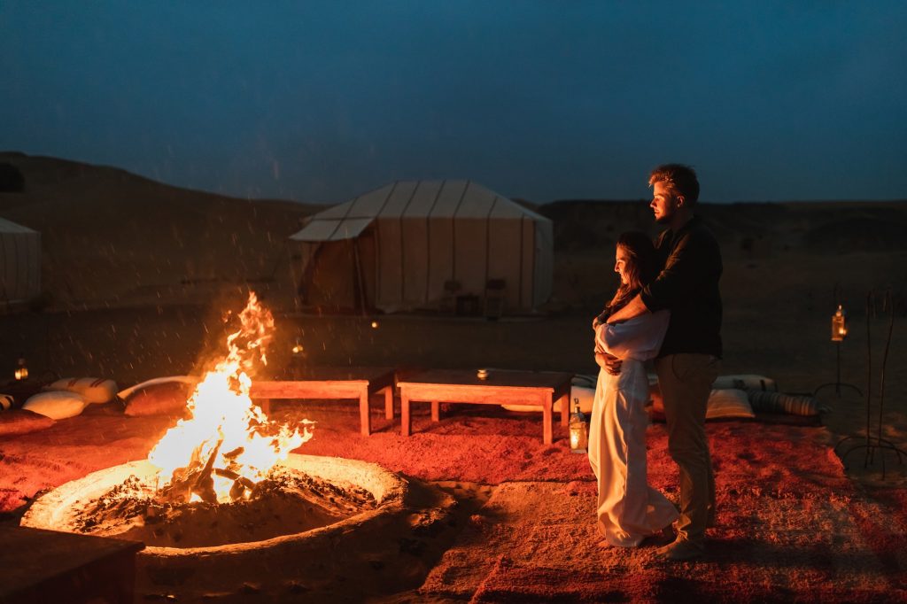 Couple hug in love near big campfire. Romantic night in glamping desert camp in Sahara, Morocco